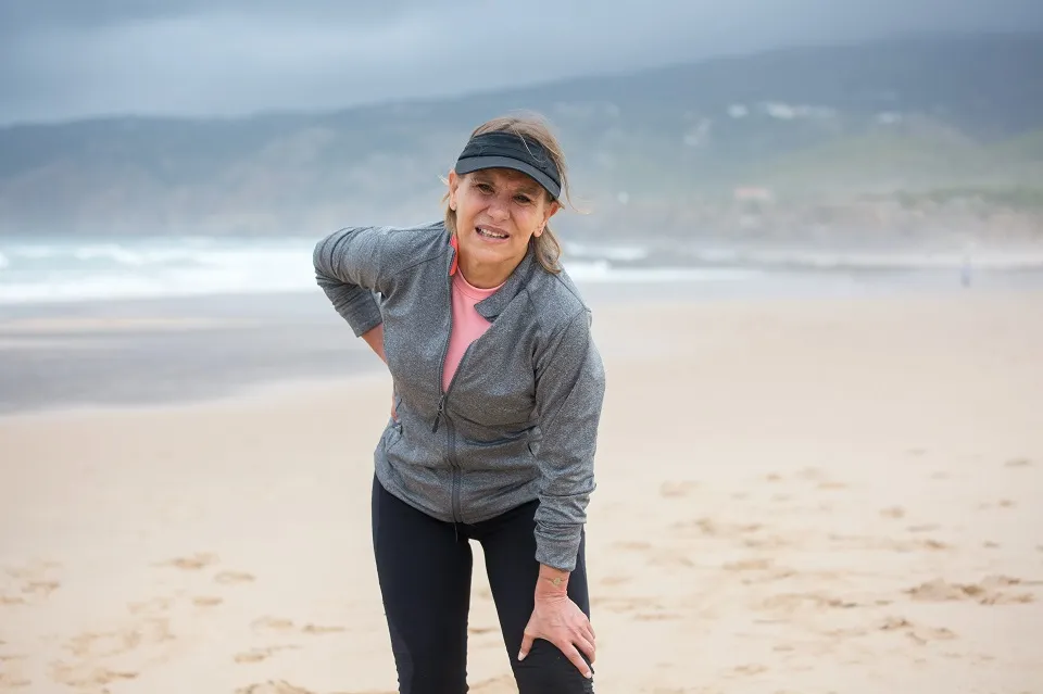 femeie pe plaja, imbracata pentru alergat