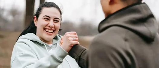 Fata imbaracata in echipament de sport care strange mana unui baiat Fata imbaracata in echipament de sport care strange mana unui baiat